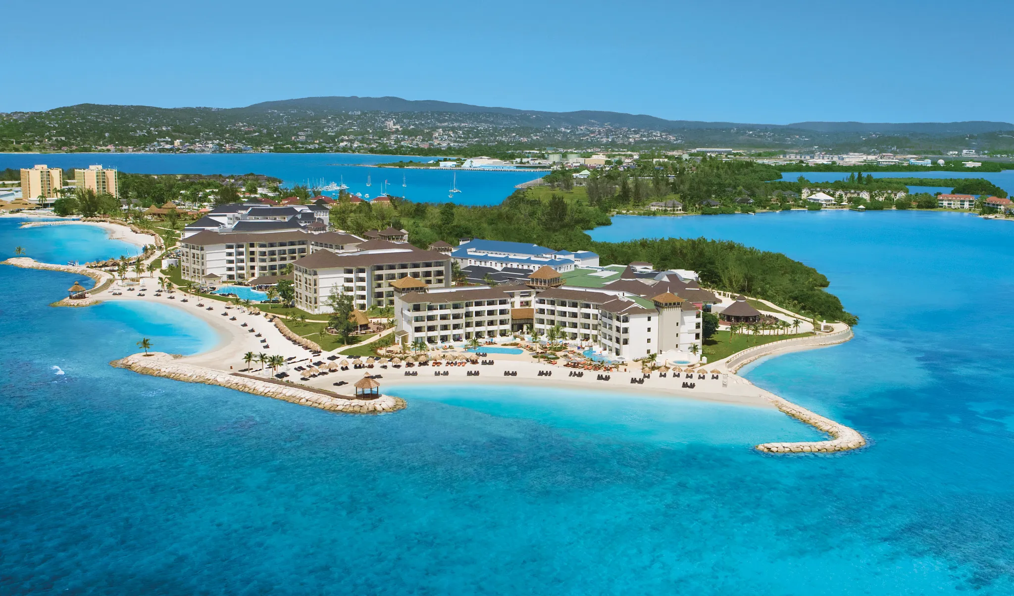 Close aerial view of Secrets St. James Montego Bay with beachfront pools, lounge areas, and calm Caribbean waters.