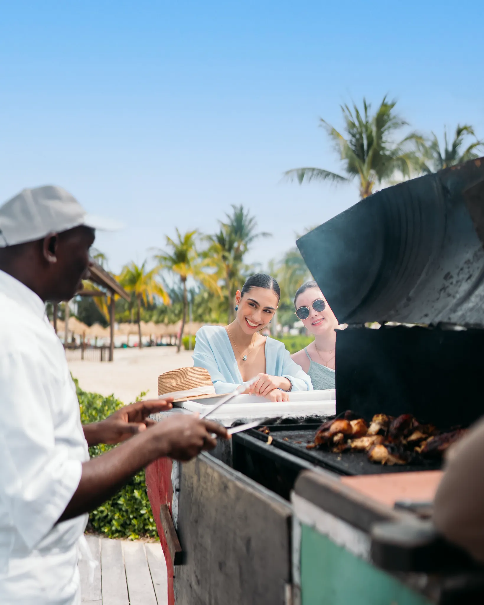 Guests enjoying freshly grilled Jamaican jerk chicken at a beachside grill at Secrets St. James Montego Bay.