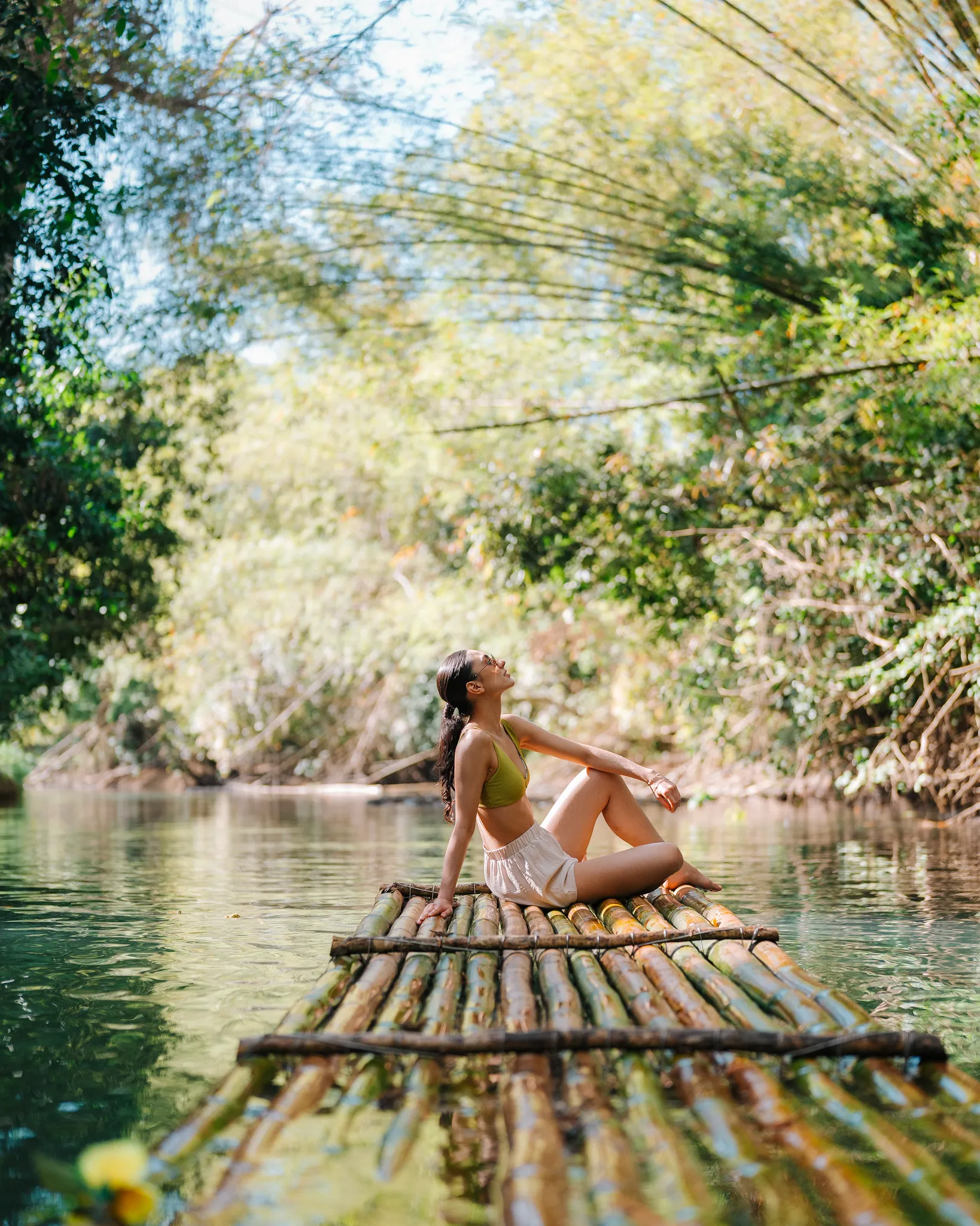 Woman relaxing on a bamboo raft along the Martha Brae River near Secrets St. James Montego Bay, enjoying a peaceful tropical excursion in Jamaica.