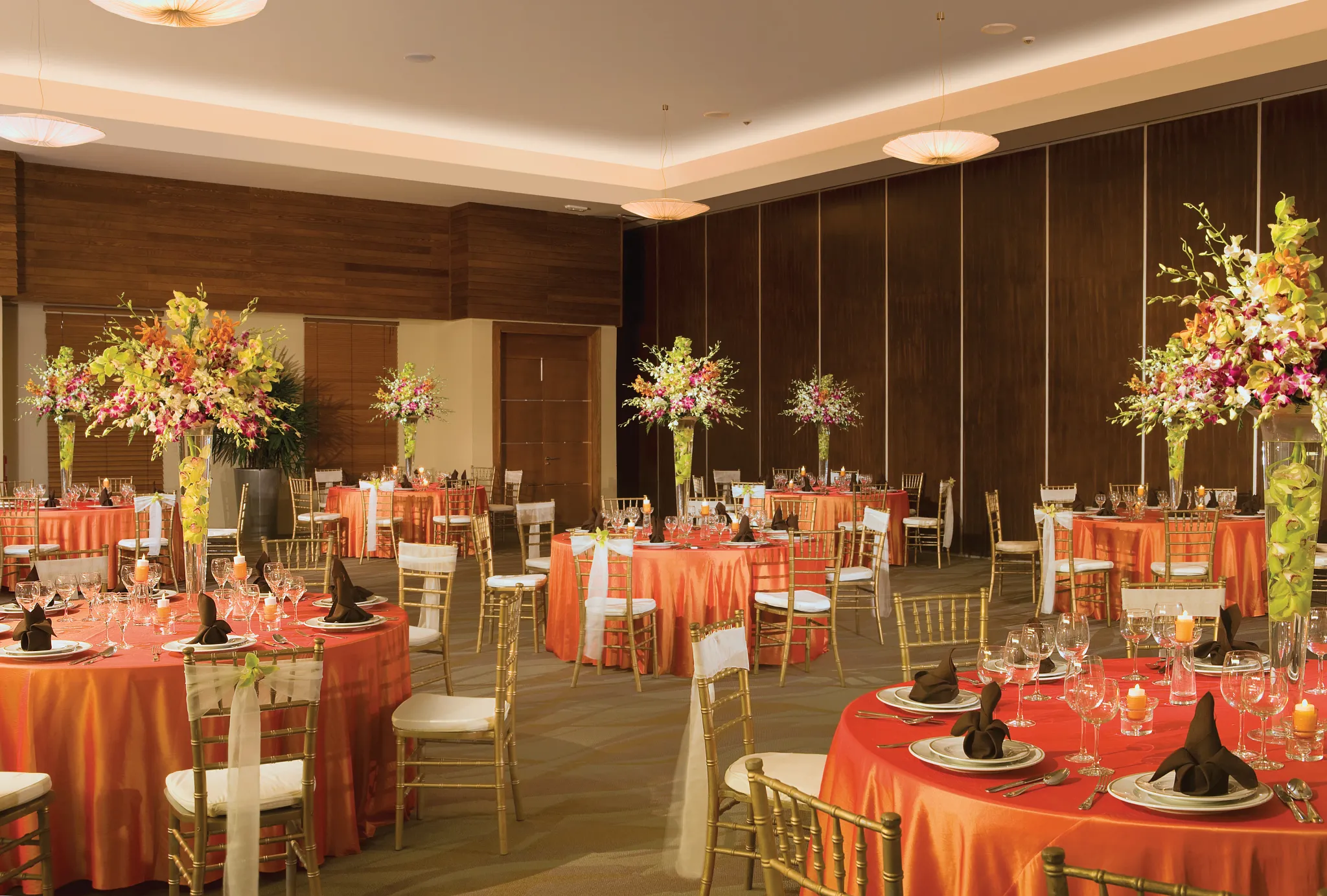 Elegant ballroom reception setup with orange linens and floral centerpieces at Secrets St. James Montego Bay